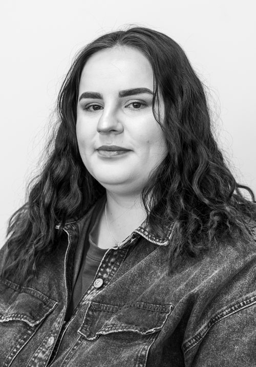 alanah-ray - Sellar & Sellar Black-and-white portrait of a woman with shoulder-length wavy dark hair wearing a denim jacket and a calm expression